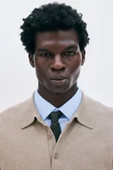 Remera polo de manga larga en punto fino color beige, con cuello clásico y tapeta de dos botones. Presenta remates acanalados en puños y bajo.