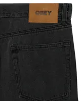 Pantalón de jean estilo baggy, de corte holgado y tiro medio, en color negro lavado. Cuenta con cinco bolsillos tradicionales, cierre de botón y bragueta con cremallera.