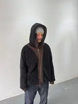 Campera reversible con cierre frontal. Un lado confeccionado en algodón color marrón con estampa plastisol en color naranja, bordados con apliques y capucha. El otro lado confeccionado en tela polar de pelo largo color negro con capucha.