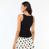 Top de punto fino negro sin mangas, con escote en V y cierre frontal con tres botones dorados decorativos. Presenta un diseño ajustado en el torso con bajo volado y peplum.
