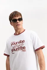 Remera de algodón blanca estilo ringer, con cuello y puños en tono marrón y estampa frontal con texto en contraste.