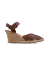 Sandalia de cuña Lora en cuero napa color marrón chocolate, con plataforma revestida en yute trenzado, puntera cerrada y tira ajustable al tobillo con hebilla forrada.