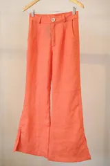 Pantalón de lino color naranja, de corte palazzo con bolsillos laterales y aberturas en el ruedo.