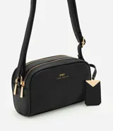 Cartera pequeña de hombro marca Satinato, confeccionada en PU con textura granulada. Presenta doble compartimento con cierre de cremallera metálica dorada, correa larga ajustable y un dije decorativo metálico con el logo de la marca.