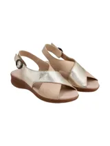 Sandalia de cuero bicolor con tiras cruzadas en el empeine, una en tono dorado metalizado y otra en color nude. Posee tira en el talón con hebilla de ajuste lateral y suela de goma con textura símil corcho.