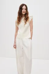 Top de algodón color beige claro con cuello de volados, canesú en V con jaretas y detalles bordados al frente, y mangas circulares con volados.