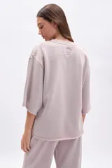 Remera oversize de manga corta con efecto lavado en color beige, cuello redondo y terminaciones deshilachadas.