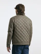 Campera capitoneada de color azul oscuro, con cierre frontal de metal y botones a presión. Presenta bolsillos laterales y en el pecho con cierres metálicos.