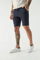 Bermuda tipo chino color verde oliva, con corte clásico, bolsillos laterales y traseros, cierre frontal y pasacintos.