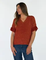 Top de punto color terracota con destellos dorados, escote en V y mangas cortas terminadas en volados con flecos.