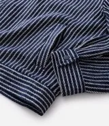 Campera masculina de corte recto con textura jacquard a rayas verticales en tonos azul marino y blanco. Presenta cuello inglés, cierre frontal con botones y manga larga.