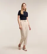 Pantalón zanahoria color beige, confeccionado en tejido airflow, con cintura alta, trabillas, cinturón con hebilla, pliegues frontales y elástico en la espalda.