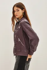 Campera estilo biker color ciruela, con múltiples cierres metálicos decorativos en el frente y mangas. Tiene cuello alto con broches, puños y cintura elastizados.