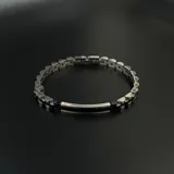 Pulsera de eslabones de acero inoxidable con placa central decorativa en tono plateado y detalle lineal en negro.