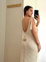 Vestido largo tejido en hilo de algodón y lurex color beige claro, con escote en V, tiras regulables en los hombros y tajos laterales. Presenta un patrón de puntos calados en forma de zigzag.