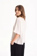 Blusa de lino color crudo, de manga corta con detalles de volados en las mangas y en el ruedo.