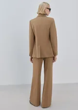 Pantalón de vestir tostado de tiro medio, con pernera ancha y recta, bolsillos laterales y pliegue planchado central.