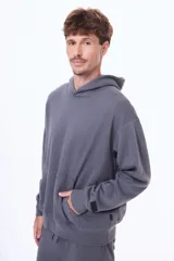 Buzo tipo canguro de felpa color gris, con capucha amplia, bolsillo frontal tipo canguro y puños acanalados.