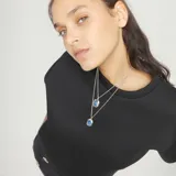 Collar doble de cadena fina bañado en plata, con dos dijes rectangulares que contienen cristales facetados en color azul.