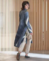 Tapado largo de lana merino afieltrada, color fucsia con diseño tie-dye artesanal en tonos claros y crudos. Tiene cuello que se prolonga a modo de cinto, aberturas laterales y bolsillos.