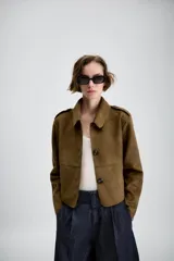 Chaqueta corta de efecto ante en color marrón, con cuello solapa, manga larga y trabillas en los hombros. Presenta cierre frontal con botones y bolsillos delanteros de doble vivo.