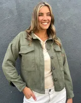 Sobrecamisa verde de gamuza sintética, estilo chaqueta de media estación, con bolsillos frontales con solapa y cierre de botones oscuros.