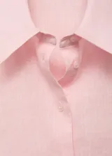Camisa de manga corta color rosado, de diseño recto con cuello camisero y cierre frontal de botones.