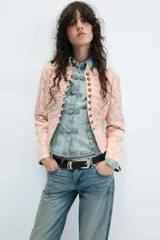 Blazer entallada de cuello alto y manga larga, en color rosado con estampado de flores amarillas. Cuenta con detalle de pasamanería en el delantero y cierre frontal con botones metálicos dorados.