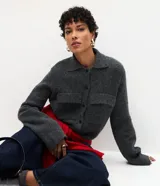 Campera de punto con textura, corte recto y cuello clásico. Presenta cierre frontal con botones y dos bolsillos aplicados con solapa en el pecho.