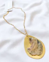 Collar con cadena dorada y colgante con base ovalada dorada y pieza de nácar irregular con orificios.