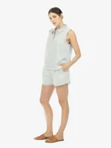 Musculosa de denim celeste, con cuello polo, escote en V con botones, de fit amplio y terminación desflecada en el bajo.