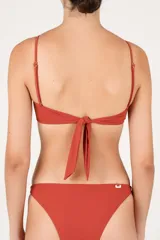 Top de bikini bandeau con abertura circular central, argolla decorativa, fruncido frontal y tirantes removibles.