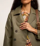 Trench coat de poliuretano color verde militar, con cuello de solapa, diseño cruzado y cierre frontal de doble botonadura.
