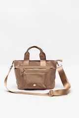 Cartera color beige de nylon con diseño compacto y funcional. Cuenta con asas cortas y correa regulable desmontable para llevar al hombro o cruzada, además de múltiples bolsillos con cierre.