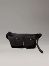 Riñonera negra de poliéster reciclado con correa ajustable con clip, cierre de cremallera en la parte superior y dos bolsillos exteriores en la parte delantera con anillas en D. Se pliega y se cierra con cremallera para crear una cartera para la muñeca.