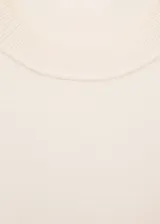 Jersey de punto fino color crema, con diseño oversize, cuello redondo y mangas cortas.