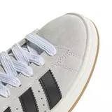 Championes urbanos adidas modelo Campus 00s, confeccionados en gamuza color gris claro con las icónicas tres tiras laterales en color negro. Presentan cordones blancos, suela de goma color crema y una base de goma natural.