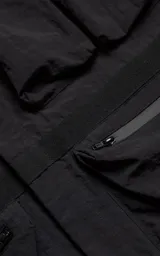 Chaqueta técnica liviana de microfibra con acabado mate, diseño con mangas desmontables que permiten convertirla en chaleco. Cuenta con cuello tipo camisa, cierre frontal oculto, cuatro bolsillos frontales de gran tamaño y puños elásticos. Incluye logo bordado en relieve en el pecho.