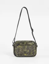 Bandolera pequeña de cuero sintético con estampado que simula cuero envejecido o craquelado en tonos verde oscuro y negro. Tiene forma rectangular rígida, cierre principal y un bolsillo frontal con cierre. Incluye correa larga ajustable y regulable.