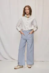 Pantalón de pierna ancha y tiro medio con diseño de rayas verticales blancas y azules. Cuenta con bolsillos delanteros amplios y cierre frontal con botón y cremallera.