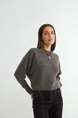 Sweater de punto negro, de corte holgado y diseño cropped, con cuello redondo y mangas largas.