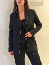 Blazer negro de corte entallado con solapas decoradas con pequeñas tachas metálicas plateadas. Presenta mangas largas y bolsillos laterales discretos.