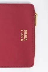 Billetera compacta de estructura blanda en color turquesa, con cierre de cremallera superior y logo metálico dorado en el frente.