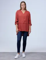 Blusa color ladrillo de crepe marca Cupio, con cuello a la base, escote en V y abertura con botones. Manga larga de largo regulable con presilla y botón. Largo de espalda mayor al largo delantero.