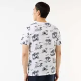 Remera blanca con estampado tropical de palmeras y paisajes en azul oscuro, de manga corta y cuello redondo.