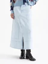 Pollera larga de denim en tono celeste claro, con diseño de paneles, bolsillos frontales y tajo central delantero.