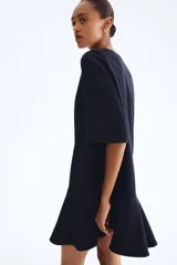 Vestido corto azul marino con finas rayas verticales blancas. Presenta cuello redondo, cierre oculto en la espalda, mangas al codo y una falda con corte circular que genera un efecto volante en el ruedo.