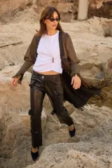 Tapado de silueta recta con estampado de cuadros, escote en V profundo y cierre frontal con un único botón. Presenta mangas largas con leve volumen, tajos laterales y terminaciones con flecos en el ruedo.