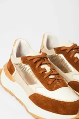 Zapatillas deportivas con base blanca y detalles en marrón, rosa y amarillo.