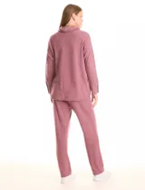 Buzo color rosado de tejido suave, con cuello volcado ajustable con lazo y mangas largas con puños decorados con botones.